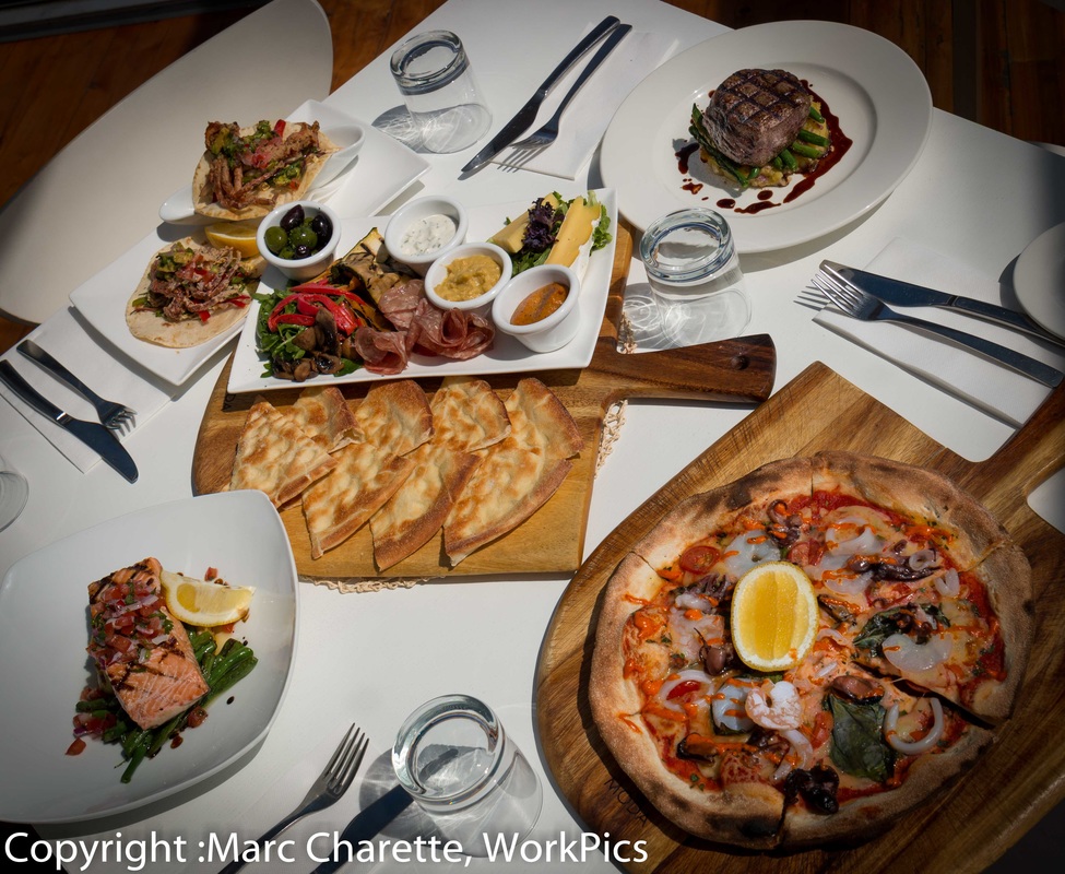 Commercial photography of restaurant table with various meals served and antipasto share platter